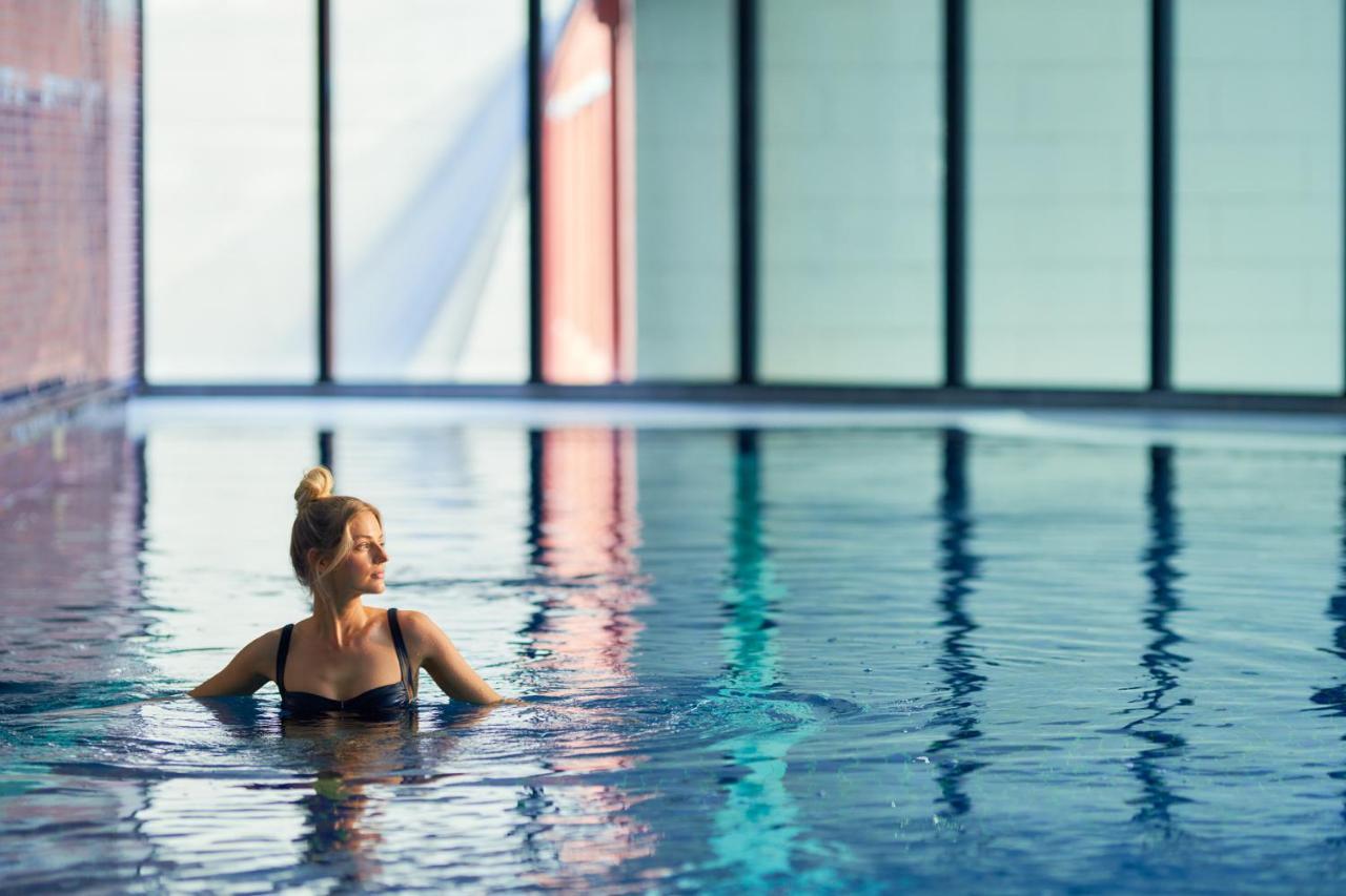 Meriton Suites Kent Street, Sydney Exterior photo The photo shows a woman in a swimming pool, partially submerged in water. She has a graceful posture and is looking thoughtfully to the side. The pool has a modern, serene atmosphere, with large windows that allow natural light to flood the space. Th